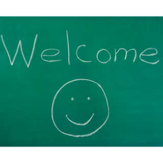 Welcome and a smiley face are written on a green chalkboard.